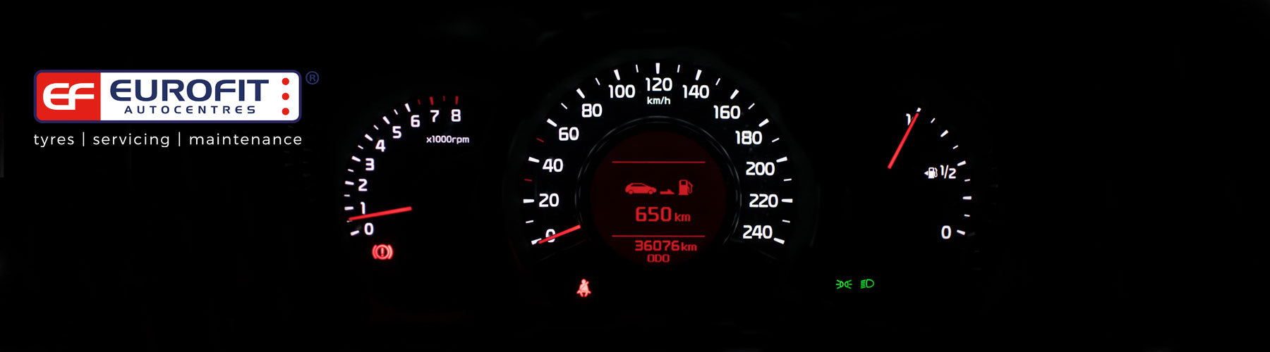 Car dashboard speedometer lit up in white and red at night 